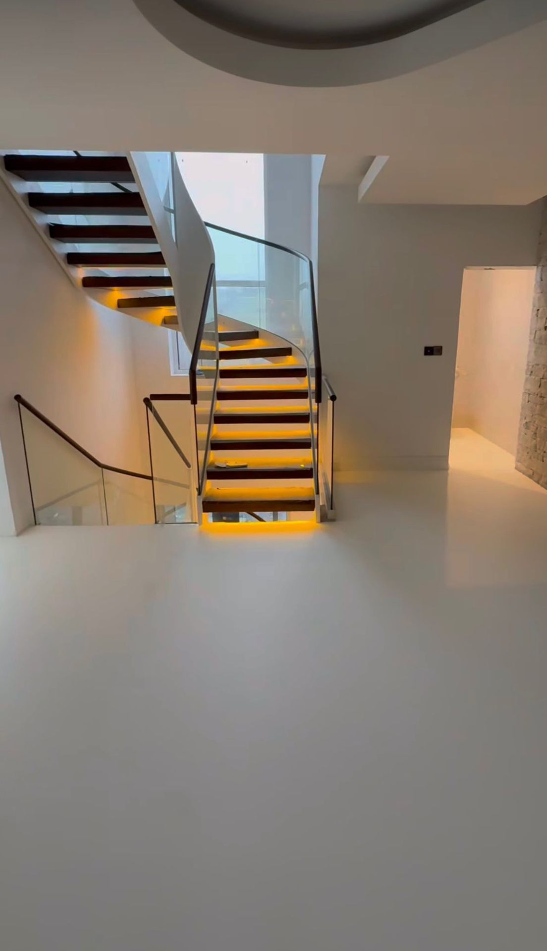 pearl PU comfort resin floor flowing under floating staircase with warm cove lighting